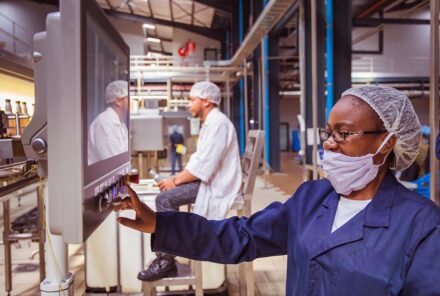 African factory workers monitoring electrical panel in beverages factory